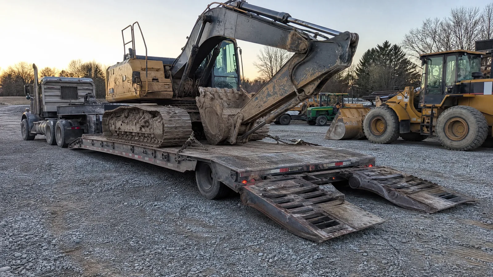 Excavator loaded on a lowboy trailer and chained at four points, ramps still down